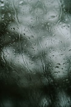Abstract view of raindrops on a window, creating a moody and textured pattern.