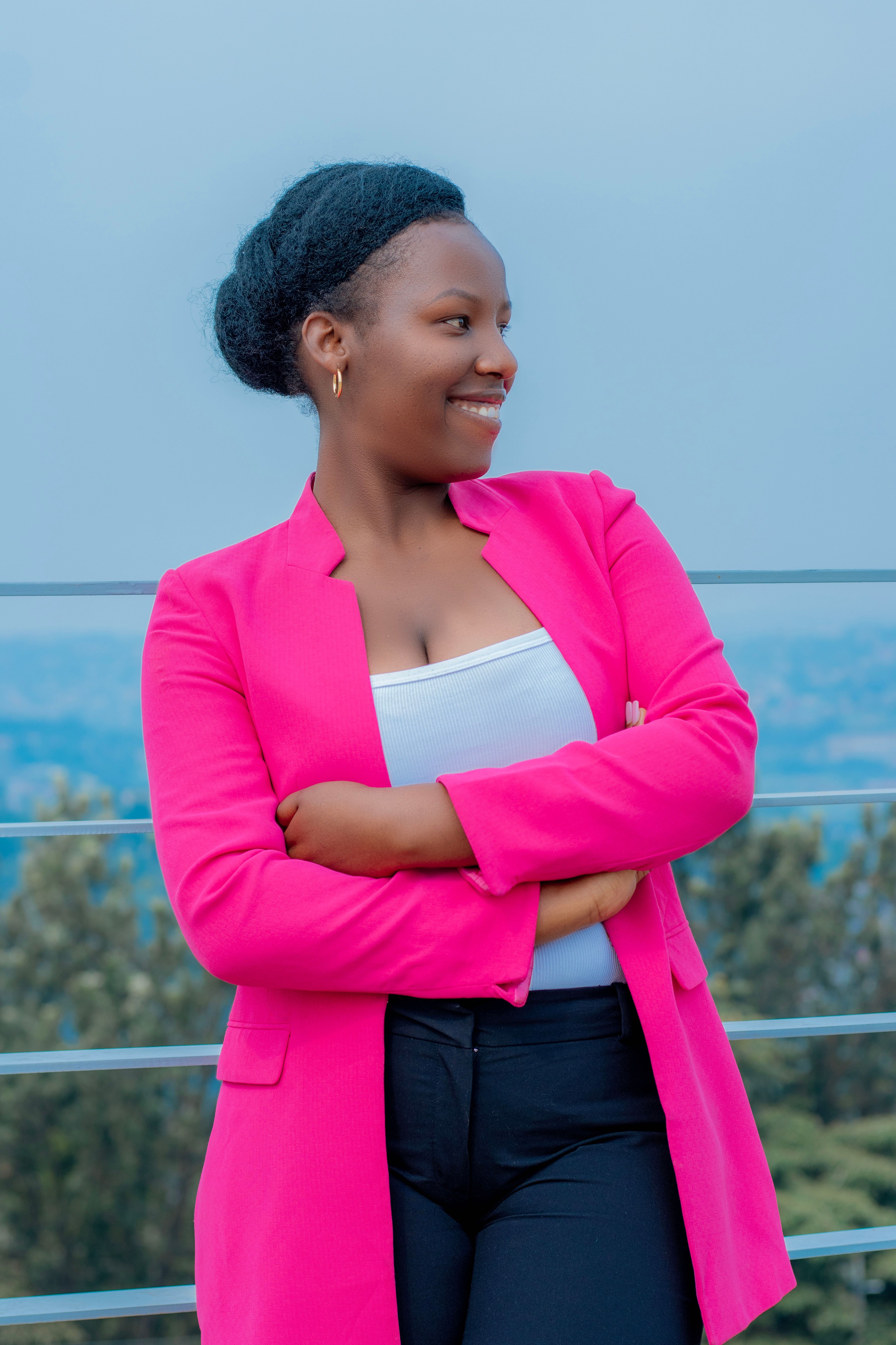 Smiling woman in pink blazer standing outdoors, capturing confidence and style against a natural backdrop.