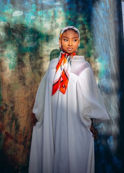 Stylish portrait of a woman in a white dress with a colorful scarf, exuding elegance.