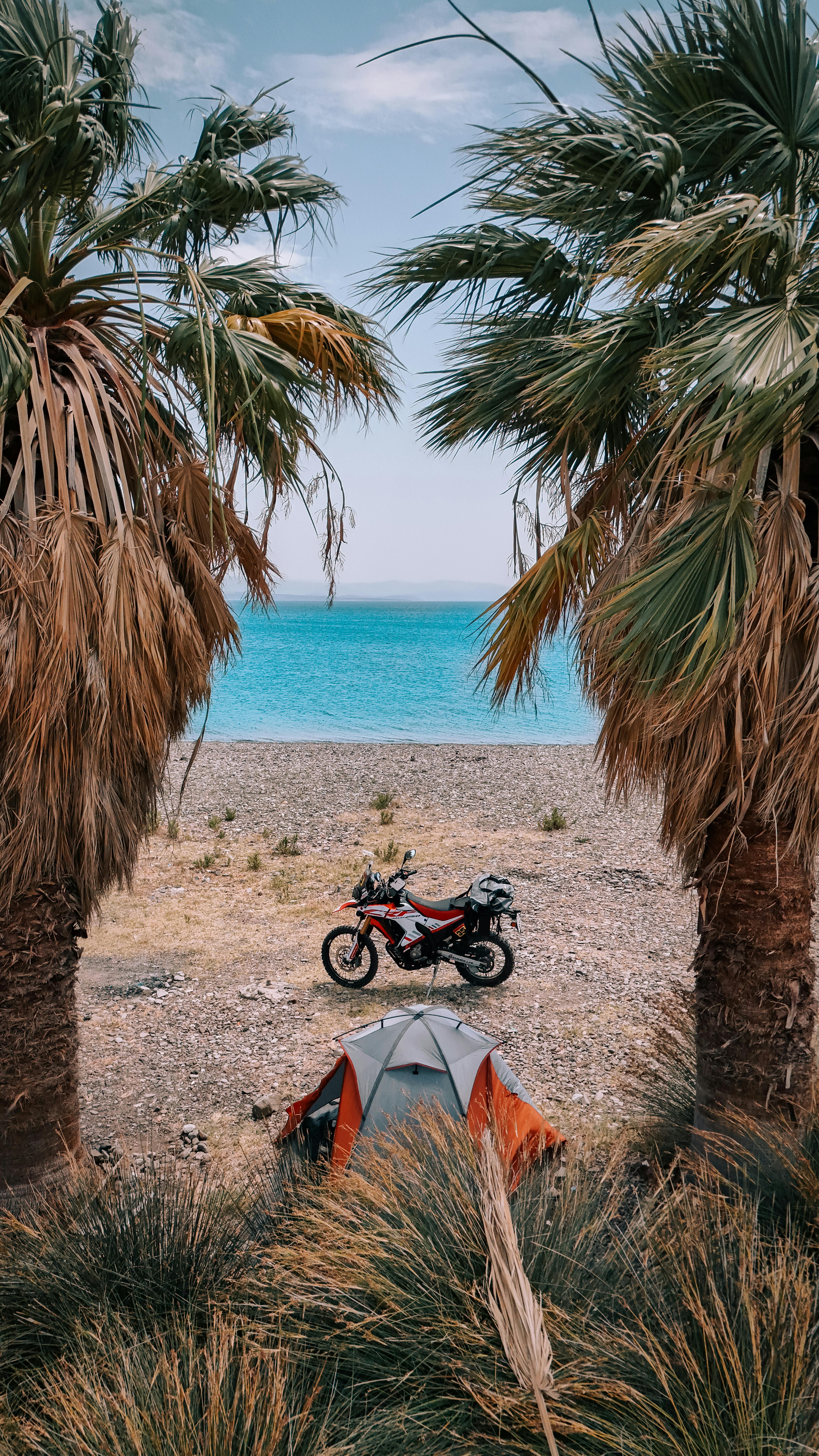 A scenic camp setup by the beach in Karaburun, İzmir with a motorcycle and tent.