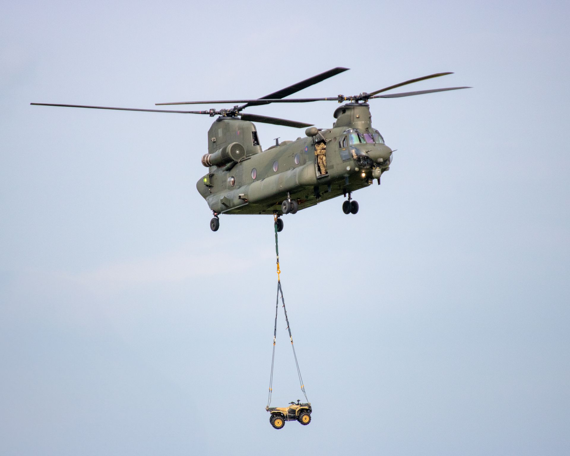 Chinook helicopter in flight transporting a military vehicle below in Albrighton, England.