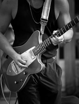 A musician passionately playing an electric guitar in black and white.