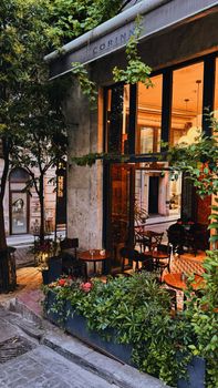 Charming outdoor seating at a cafe surrounded by greenery in urban setting.