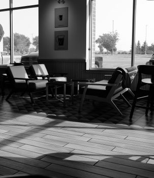 Black and white photo of a cozy coffee shop with chairs and window view.