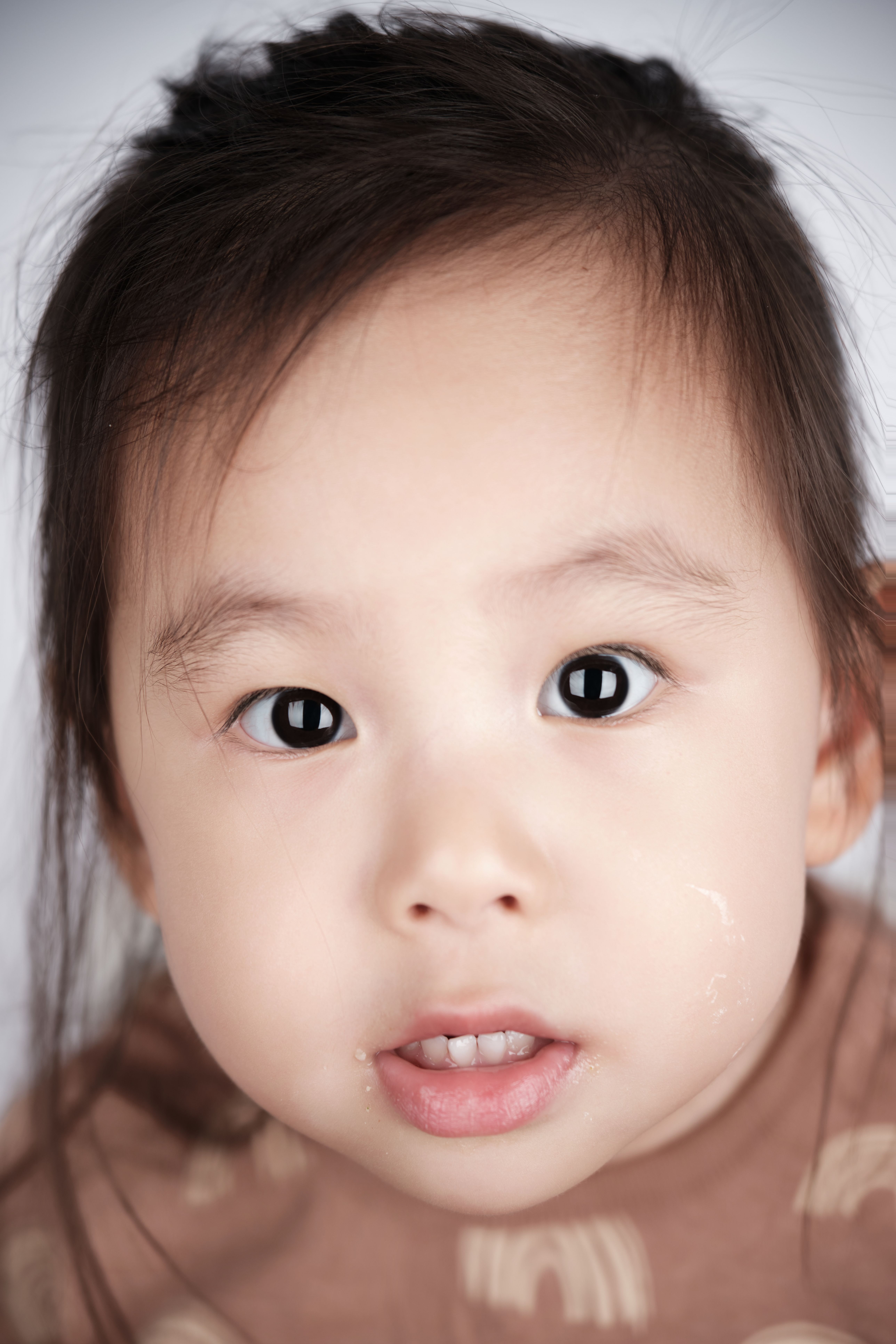 Adorable toddler with large expressive eyes, captured in a close-up portrait.