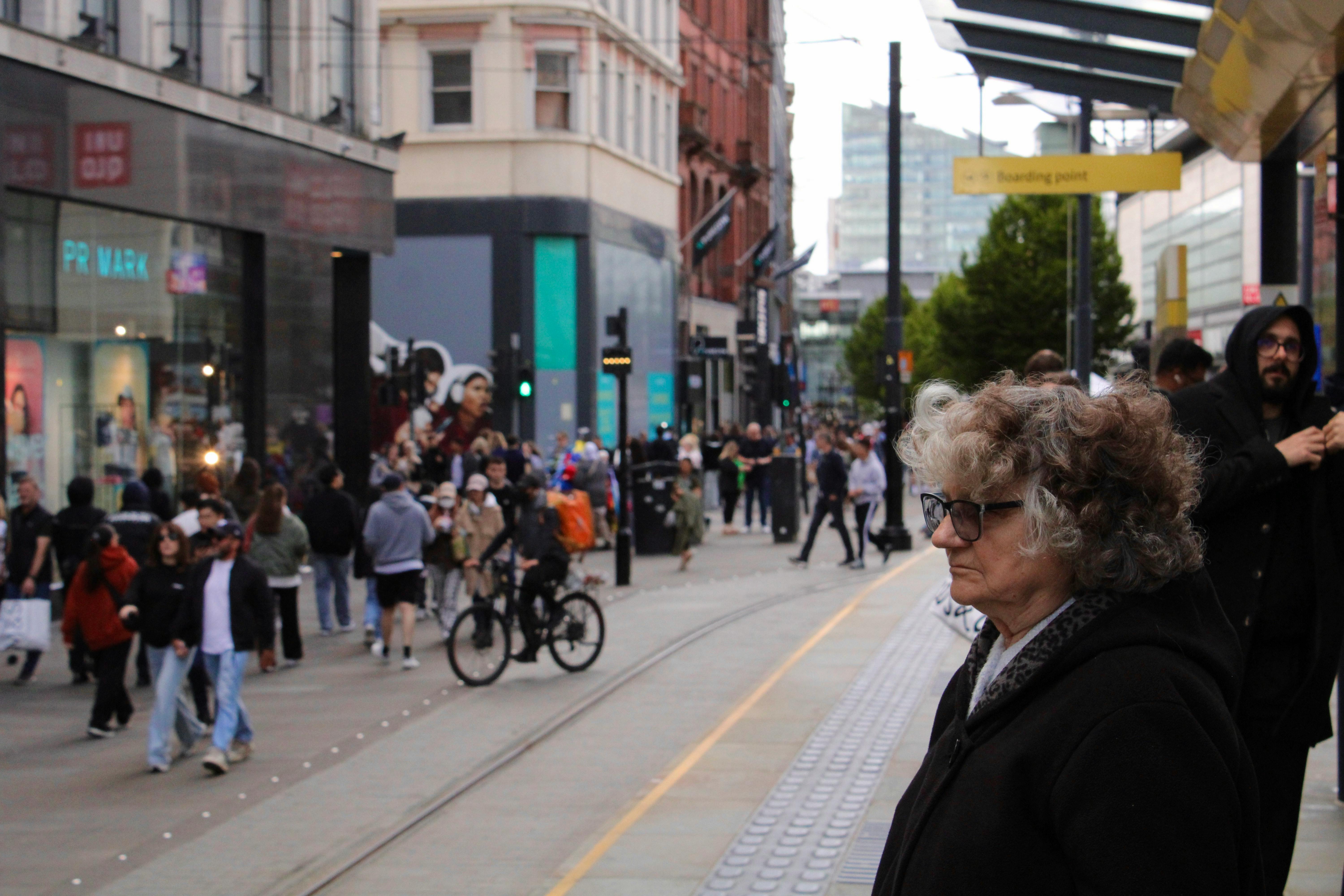 Lively city street with pedestrians, cyclists and shops.
