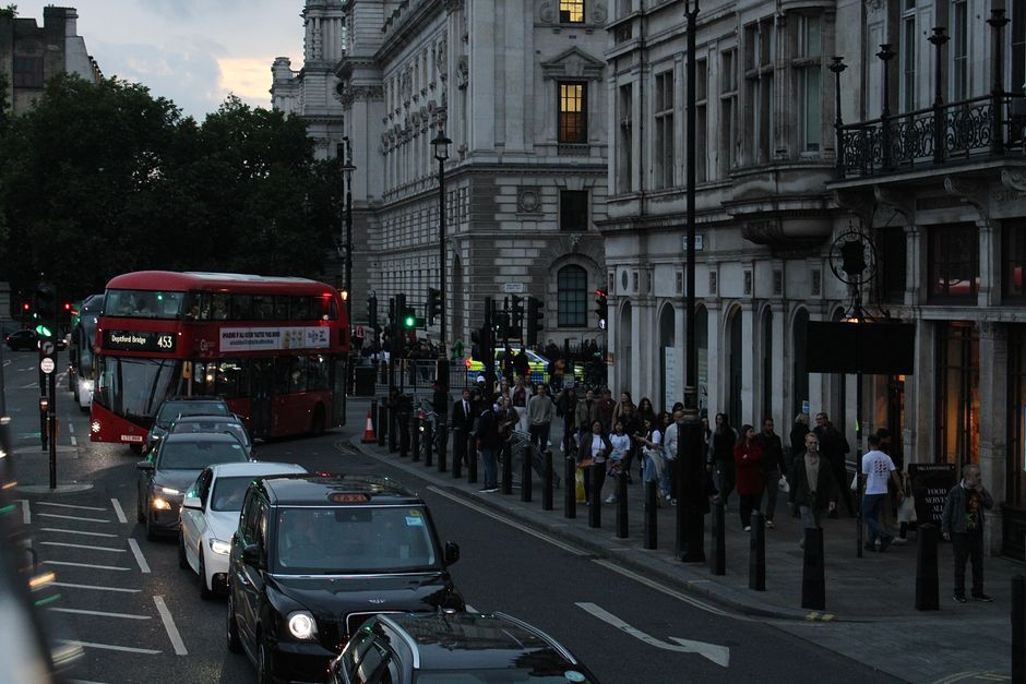 Evening scene of a busy London street with a double-decker bus and pedestrians.