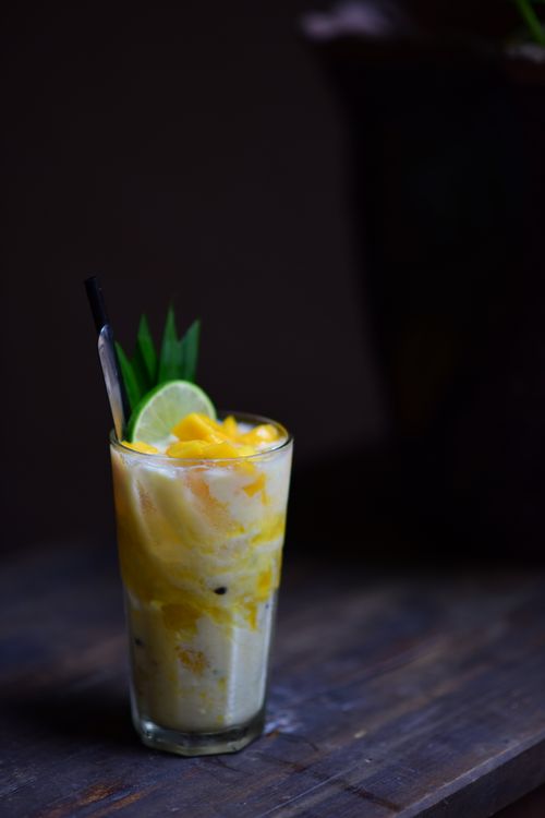 Free Tropical smoothie with mango and lime in a glass on a wooden table, perfect for summer vibes. Stock Photo