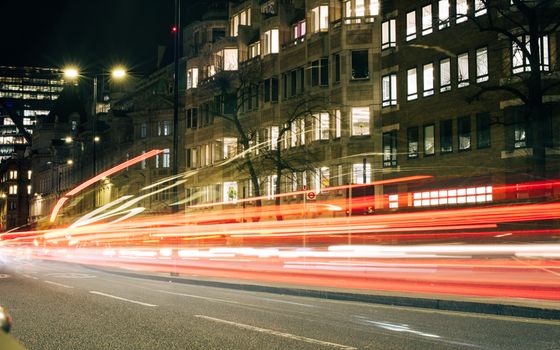 Dynamic night scene capturing long exposure traffic in London, highlighting vibrant city life.