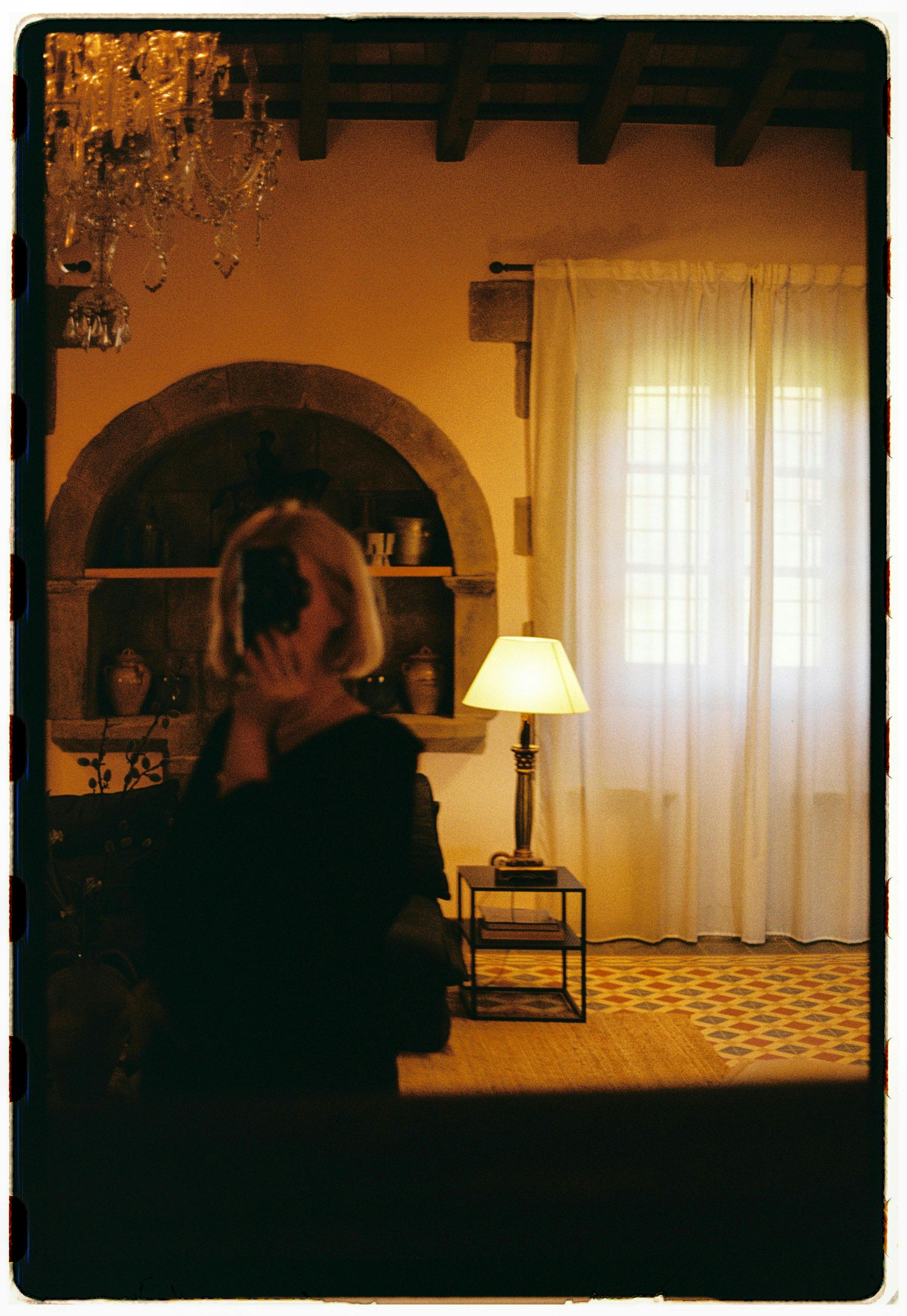 Warm, elegant room with a woman photographing herself in a mirror.