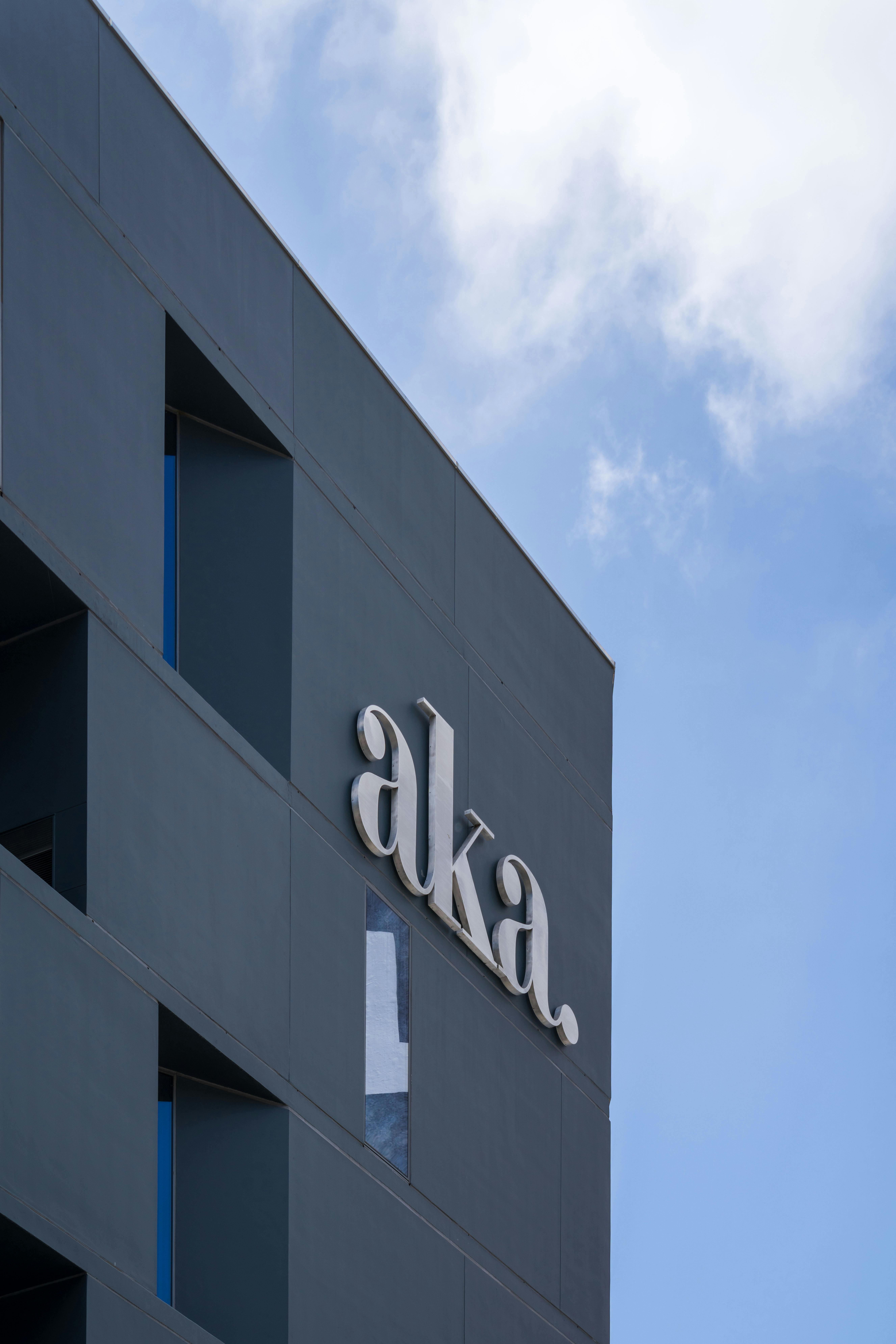 A minimalist architectural shot featuring a modern building with 'aka' signage under a clear blue sky.