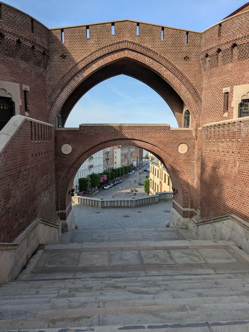 Free View through a historic brick archway framing a city street scene in the early evening light. Stock Photo