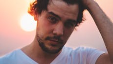 在五颜六色的日落背景下，一个面部毛发浓密的男人的特写肖像