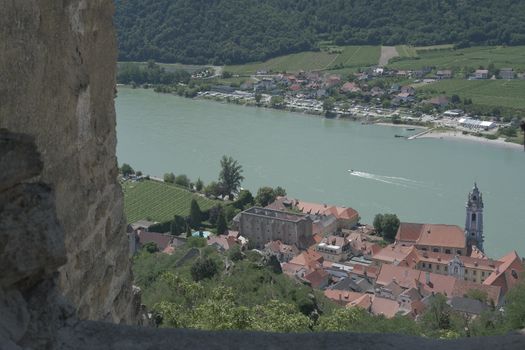 Explore the scenic view of Dürnstein and the Danube River framed by an ancient fortress wall.
