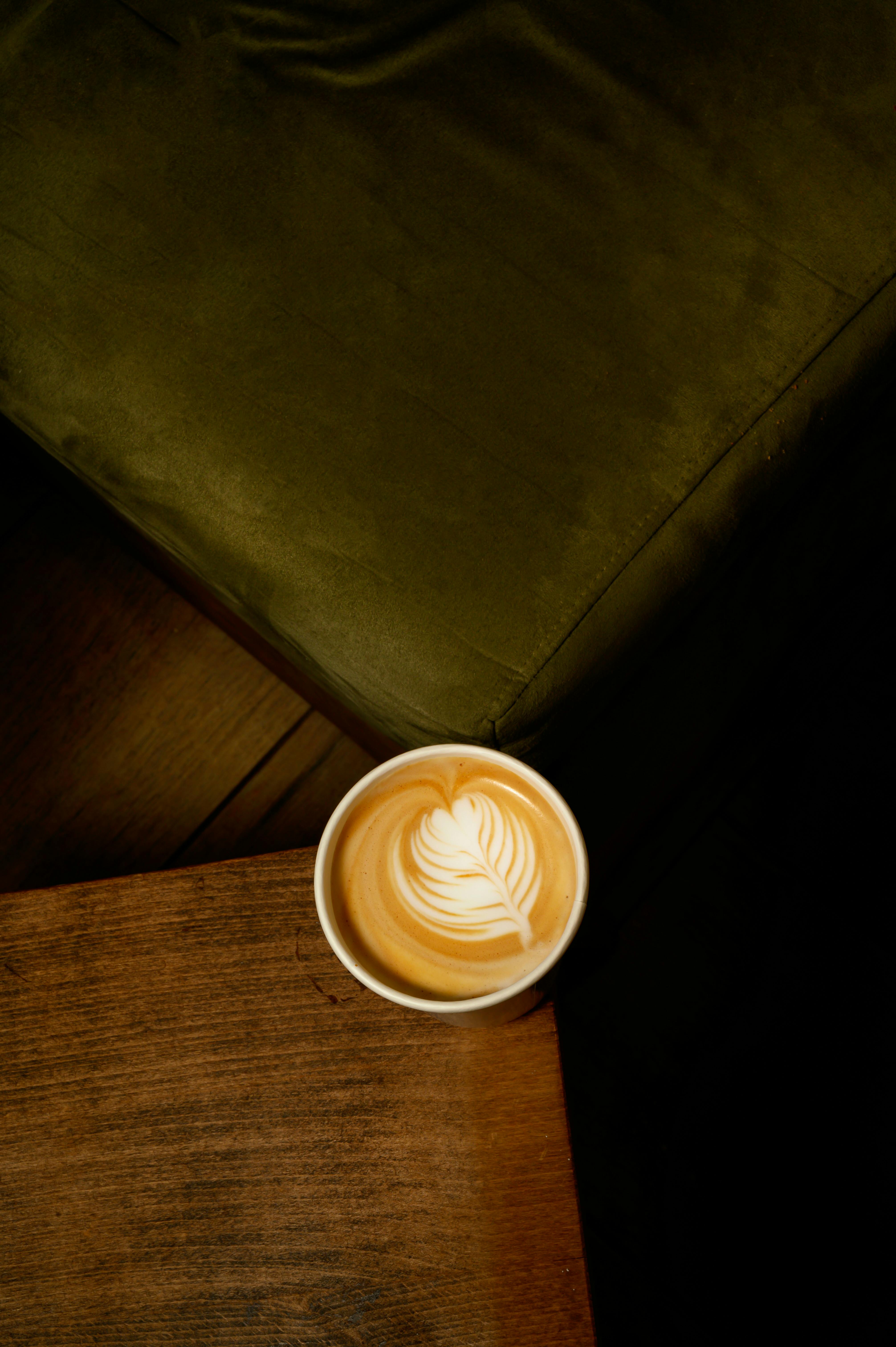 Aerial view of elegant latte art on a cappuccino in a cozy Thessaloniki cafe setting.