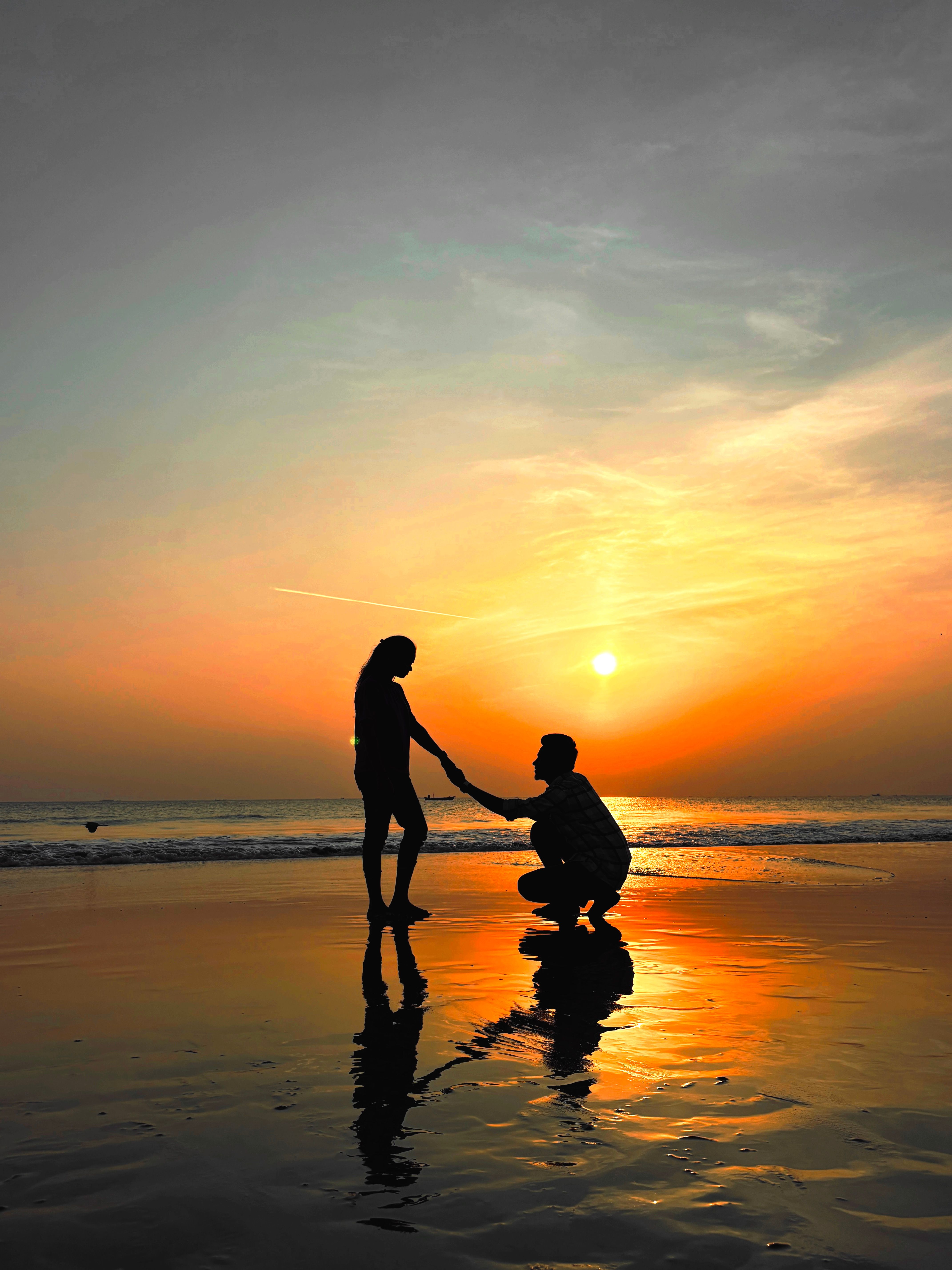Silhouette of a couple during a romantic beach proposal at sunset in India.