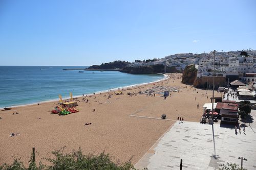 Free Aerial view of Albufeira beach, Algarve, on a sunny day with ocean waves and coastal town backdrop. Stock Photo