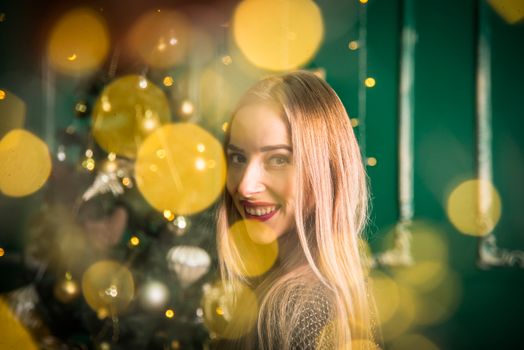 A joyful woman surrounded by festive lights, exuding warmth and holiday spirit.