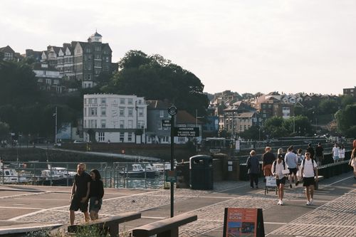 Free People strolling by a scenic harbor with historic buildings and vibrant atmosphere. Stock Photo