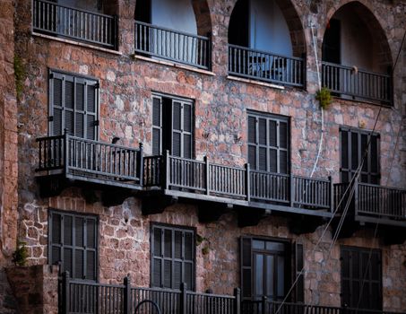 Old stone building in Gazimağusa with traditional wooden balconies, showcasing vintage architectural style.