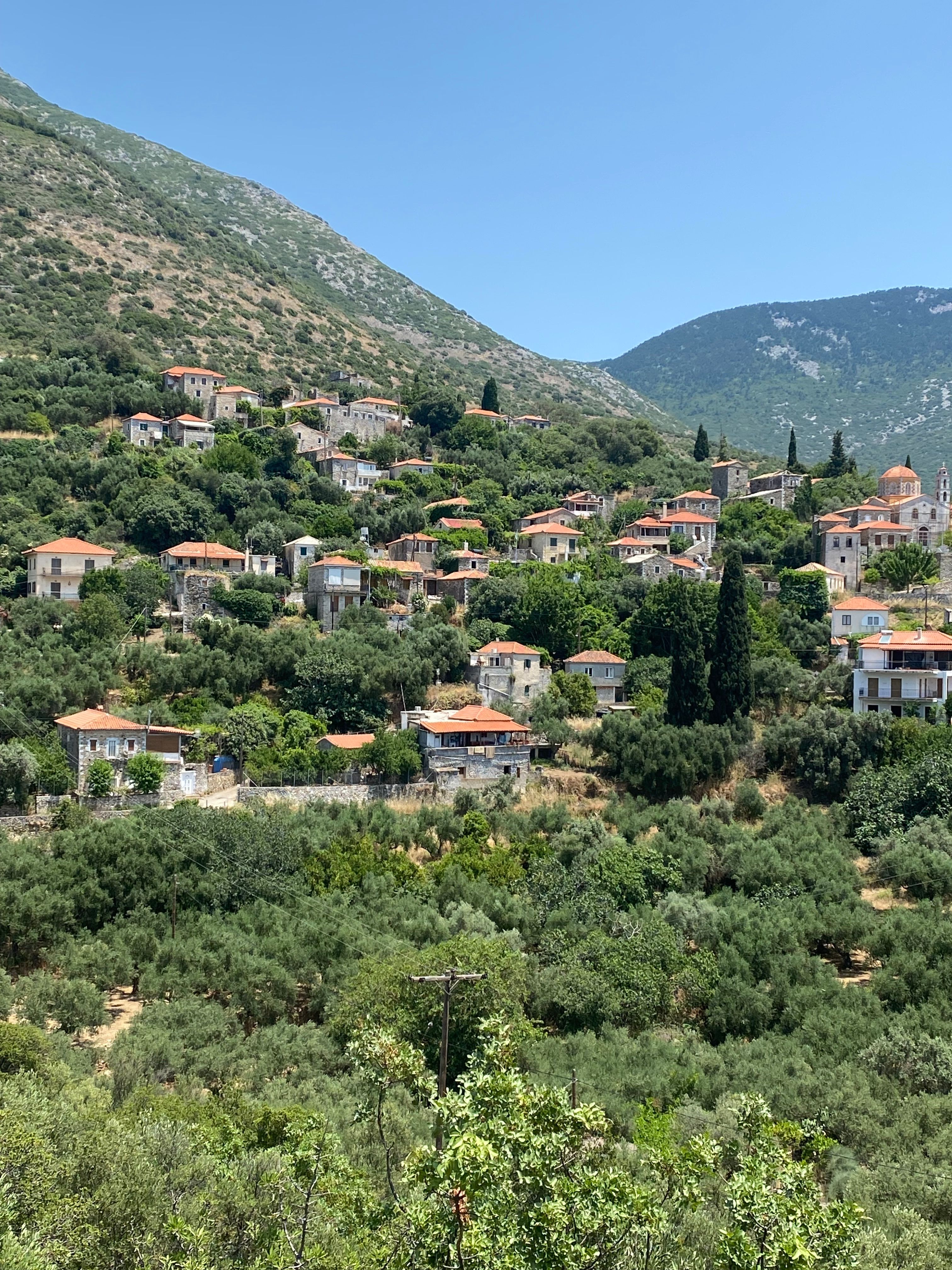 Picturesque hillside village in Lakonia, Greece with mountains and lush greenery.