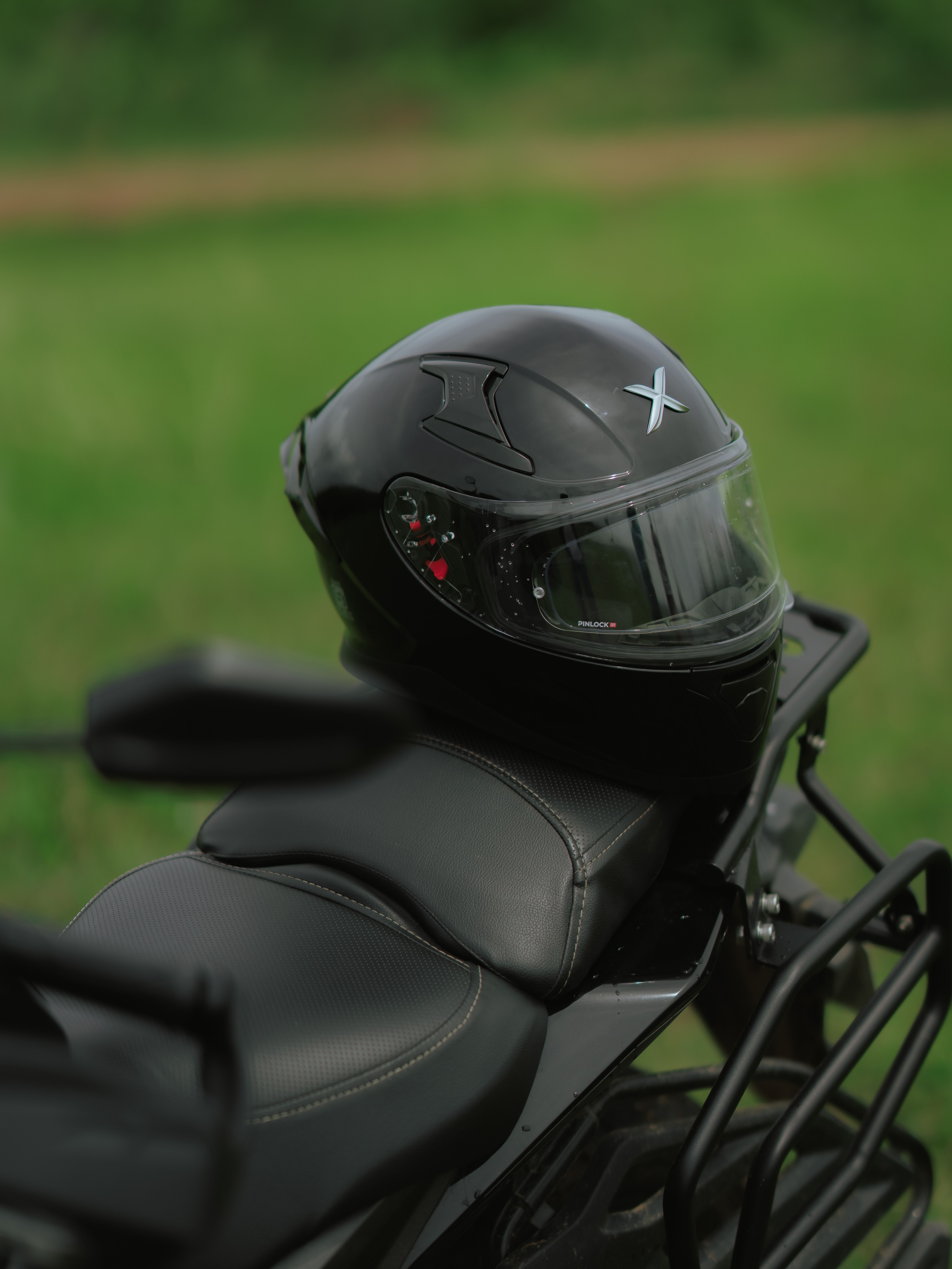 Black motorcycle helmet resting on a leather seat outdoors, emphasizing safety and style.