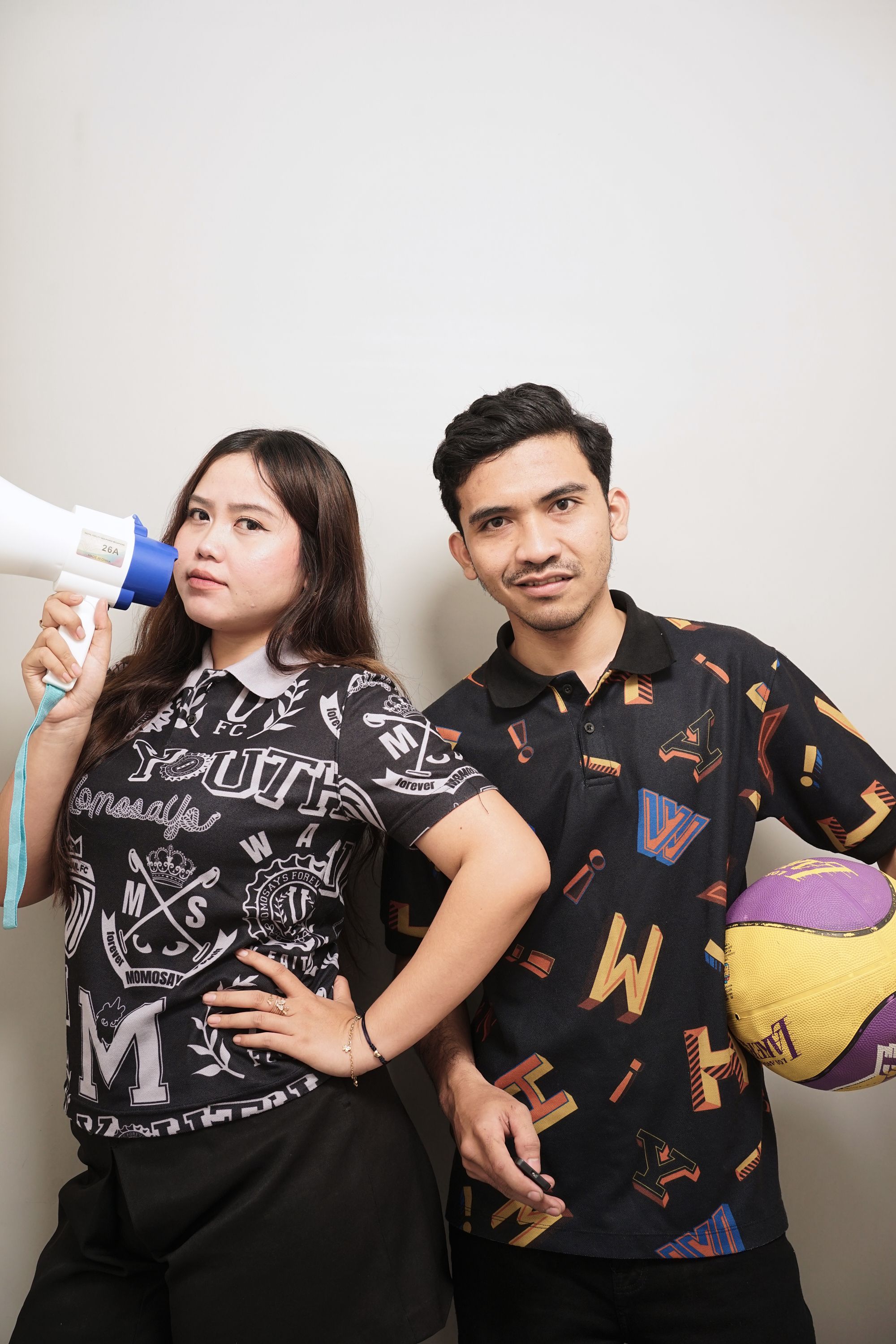 Portrait of young adults holding a megaphone and a basketball, showcasing teamwork and communication.