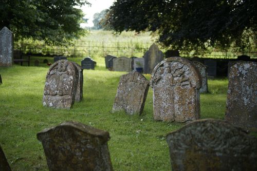 Free Old weathered headstones in a peaceful outdoor cemetery surrounded by greenery. Stock Photo