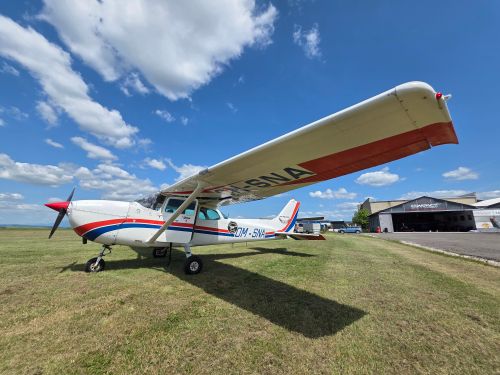 Free A light aircraft parked on a clear day near a hangar at an airport, showcasing aviation design. Stock Photo
