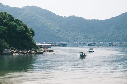 Free Peaceful lake with boat, mountains, and lush greenery creating a serene backdrop. Stock Photo