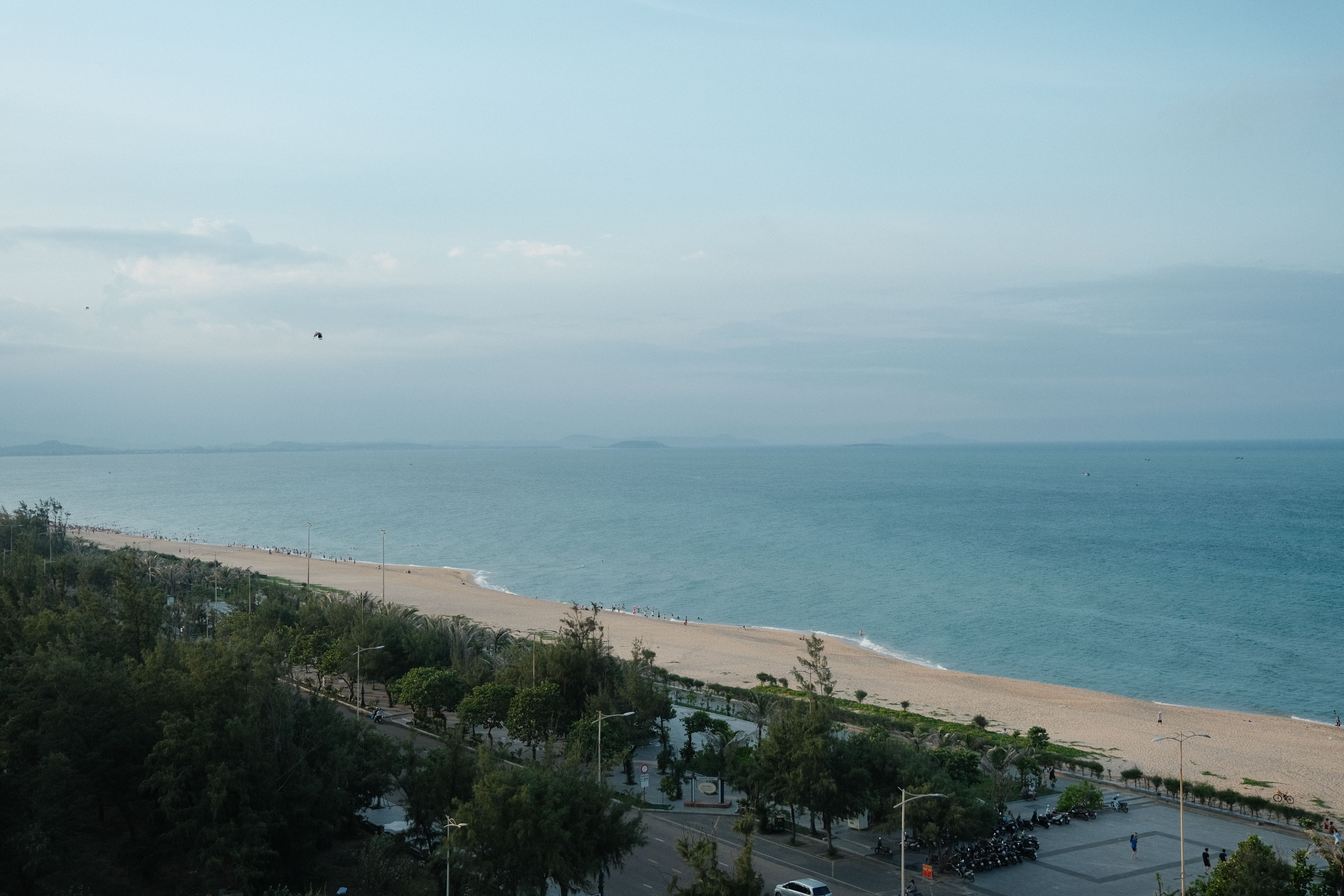 A tranquil aerial view of a beach with a road and ocean horizon, captured at dawn.