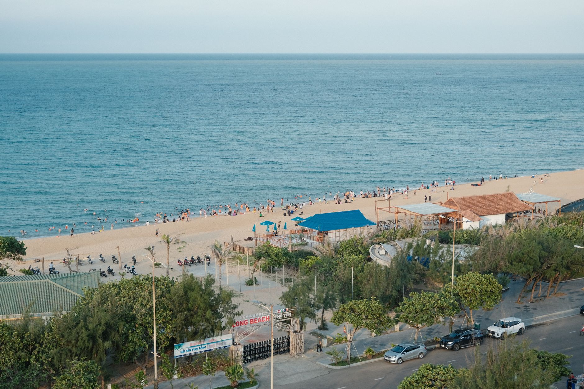 Aerial view of a vibrant sandy beach with visitors enjoying a sunny day by the sea.