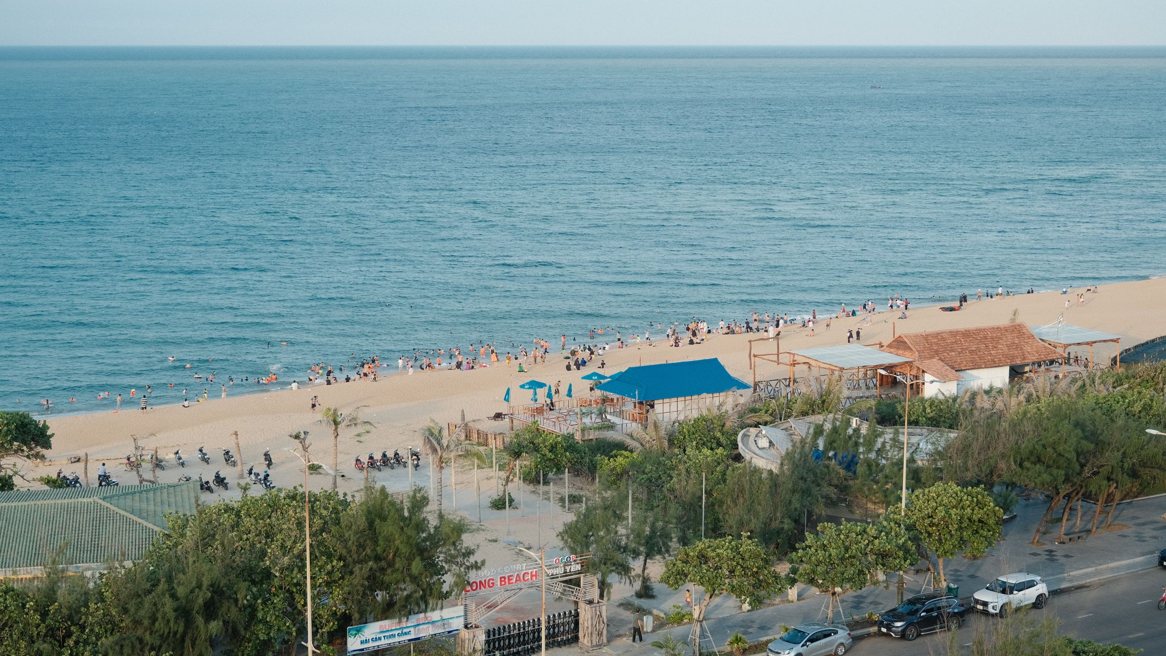 Aerial view of a vibrant sandy beach with visitors enjoying a sunny day by the sea.