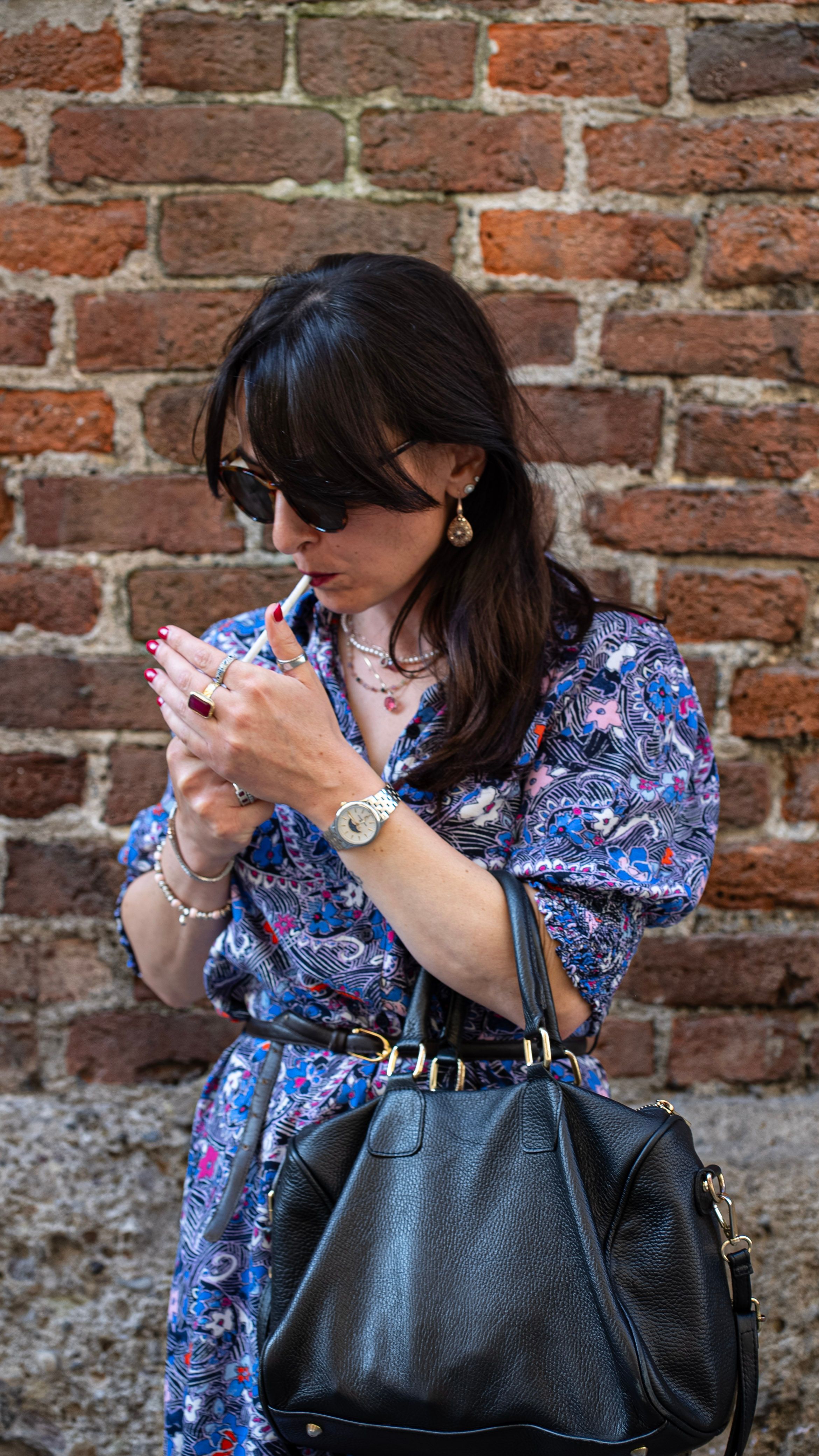 Gratis Una donna alla moda di Milano posa all'aperto con una borsa chic e occhiali da sole in una giornata di sole. Foto a disposizione