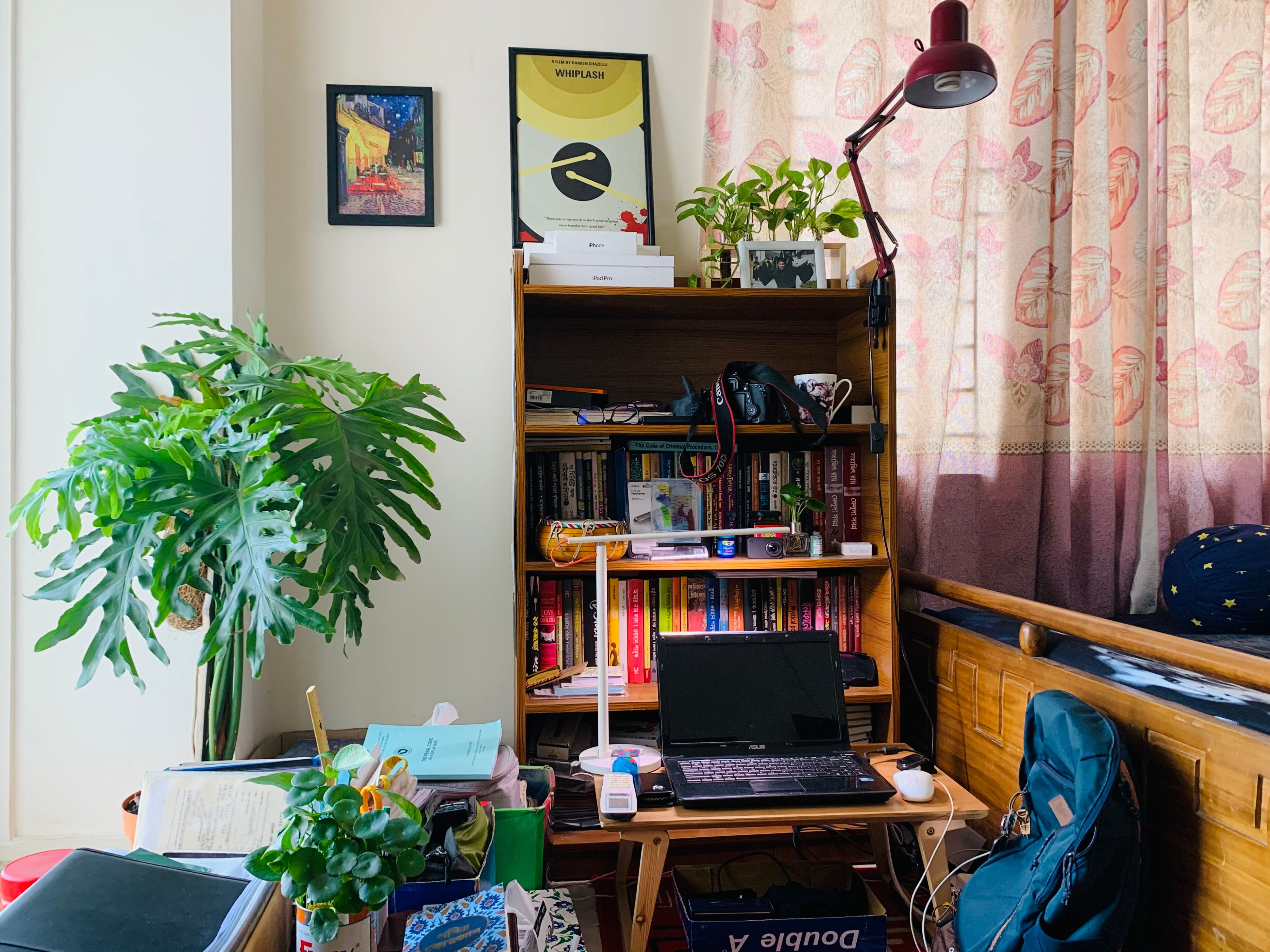 Home office com notebook, estante de livros e plantas ao fundo