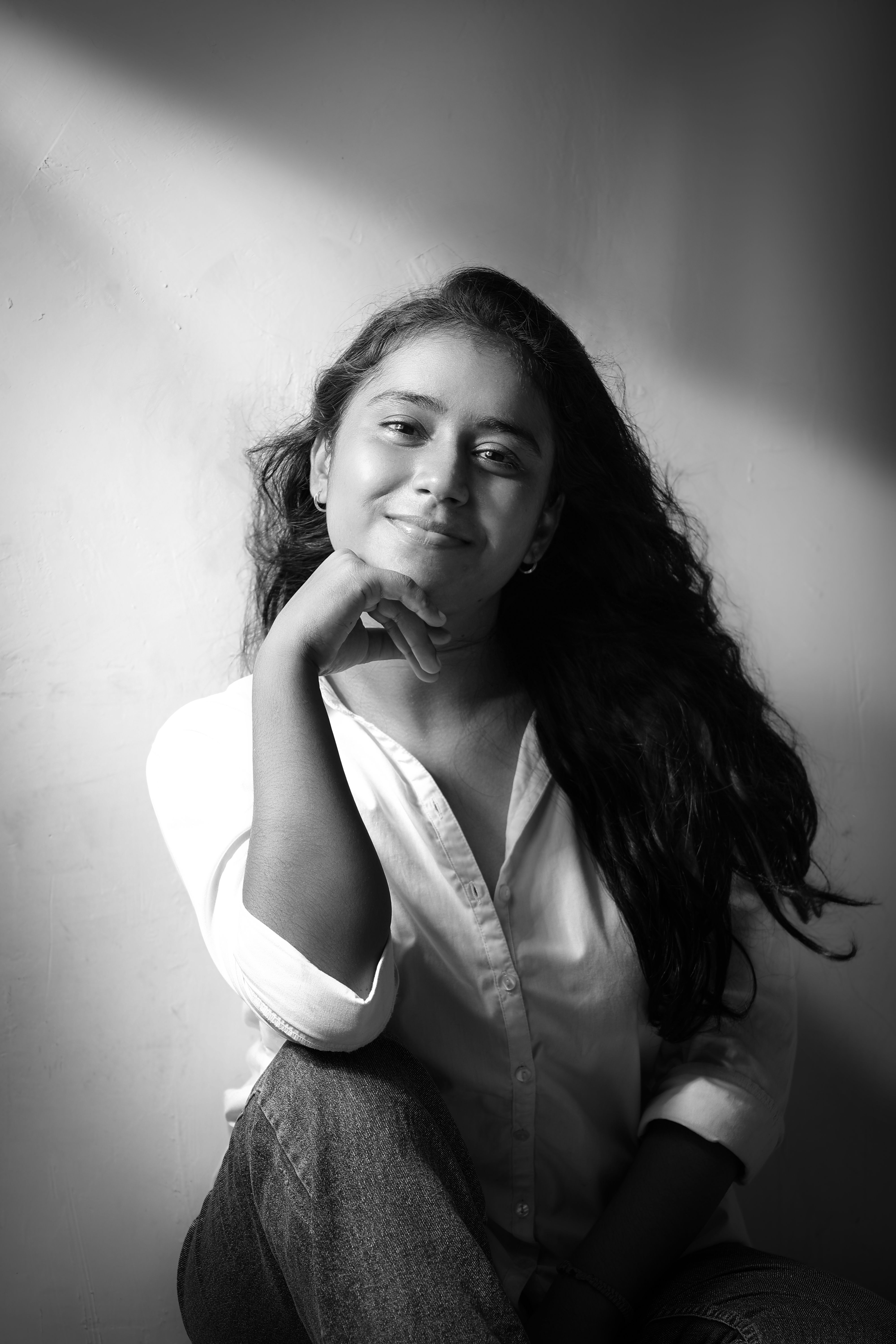 Elegant black and white portrait of a young woman smiling in relaxed pose.
