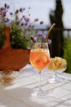 Chilled Aperol Spritz with lemon slice and straw, set on a sunny patio table surrounded by lavender.