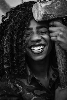 一个卷发的人微笑着拿着锤子的黑白特写