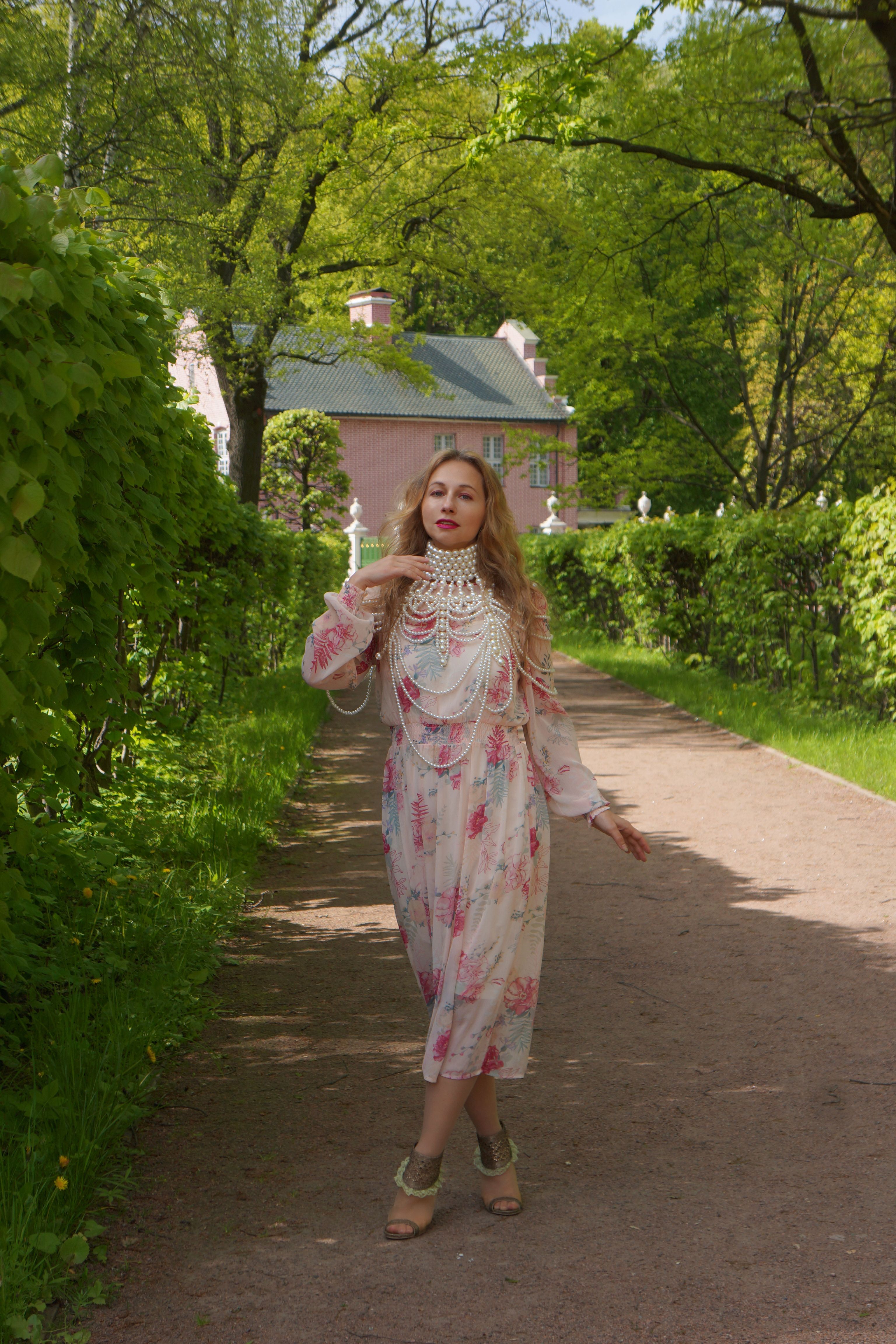Elegant Woman in Floral Dress Strolling Garden Path