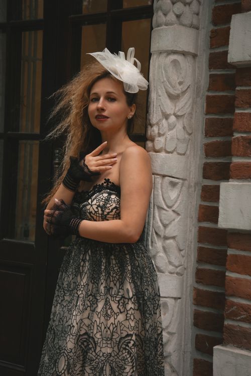 Free Stylish woman in an elegant dress poses against a textured wall. Stock Photo