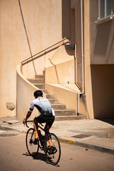 Cyclist rides by a sunlit Mediterranean building in Cargèse, showcasing Corsican charm.