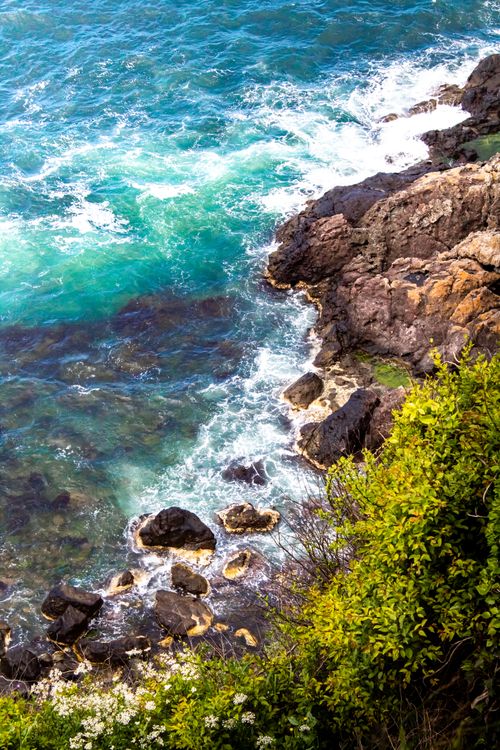 Free Aerial view of vibrant coastline with rocky cliffs and turquoise sea waves crashing. Stock Photo