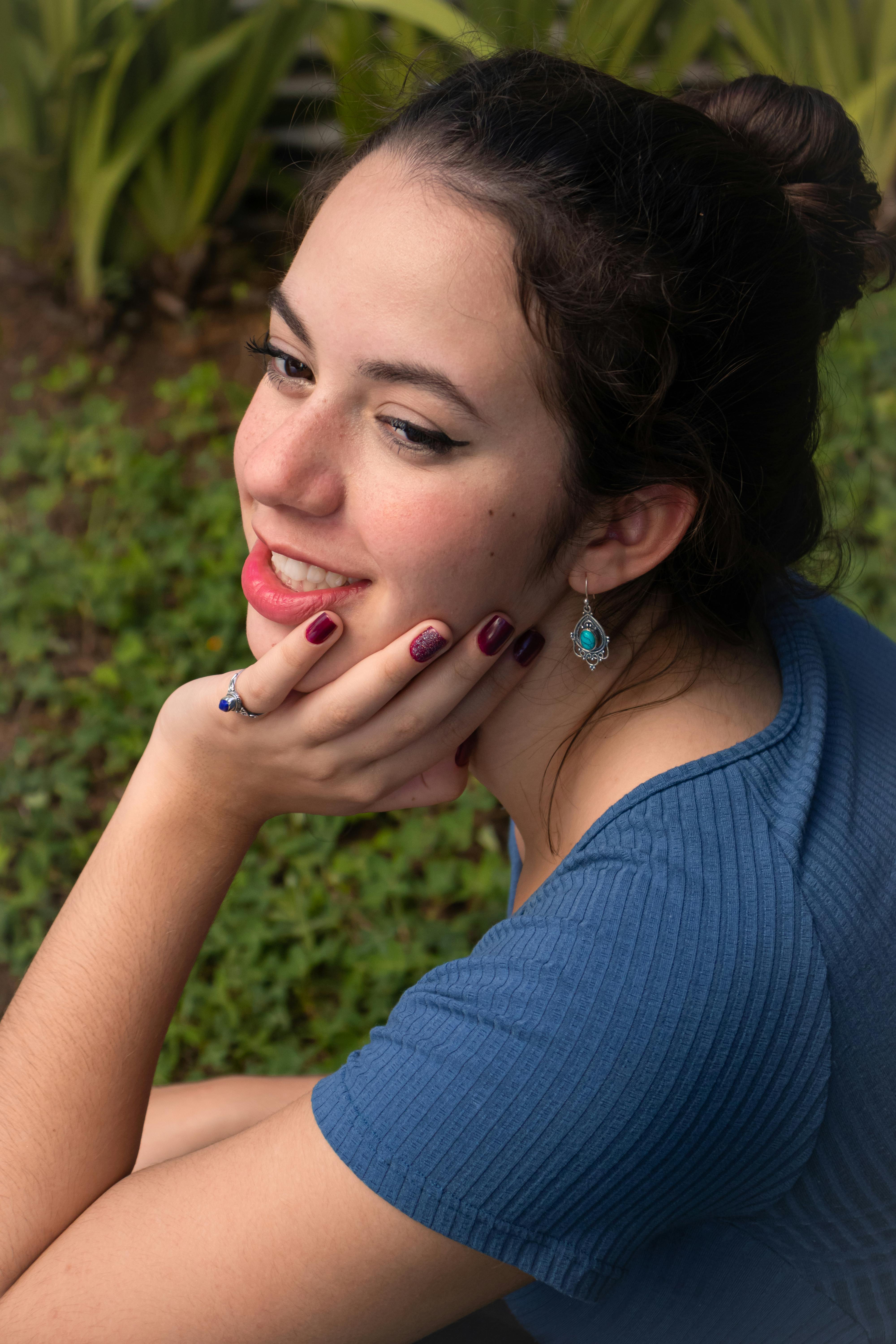 De franc Retrat en primer pla a l'aire lliure d'una dona jove somrient, amb una camisa blava i joies úniques. Foto d'estoc