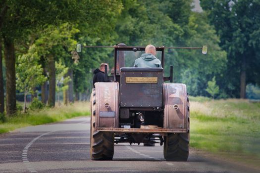 A classic Lanz Bulldog tractor driven along a leafy rural road, showcasing agricultural history.