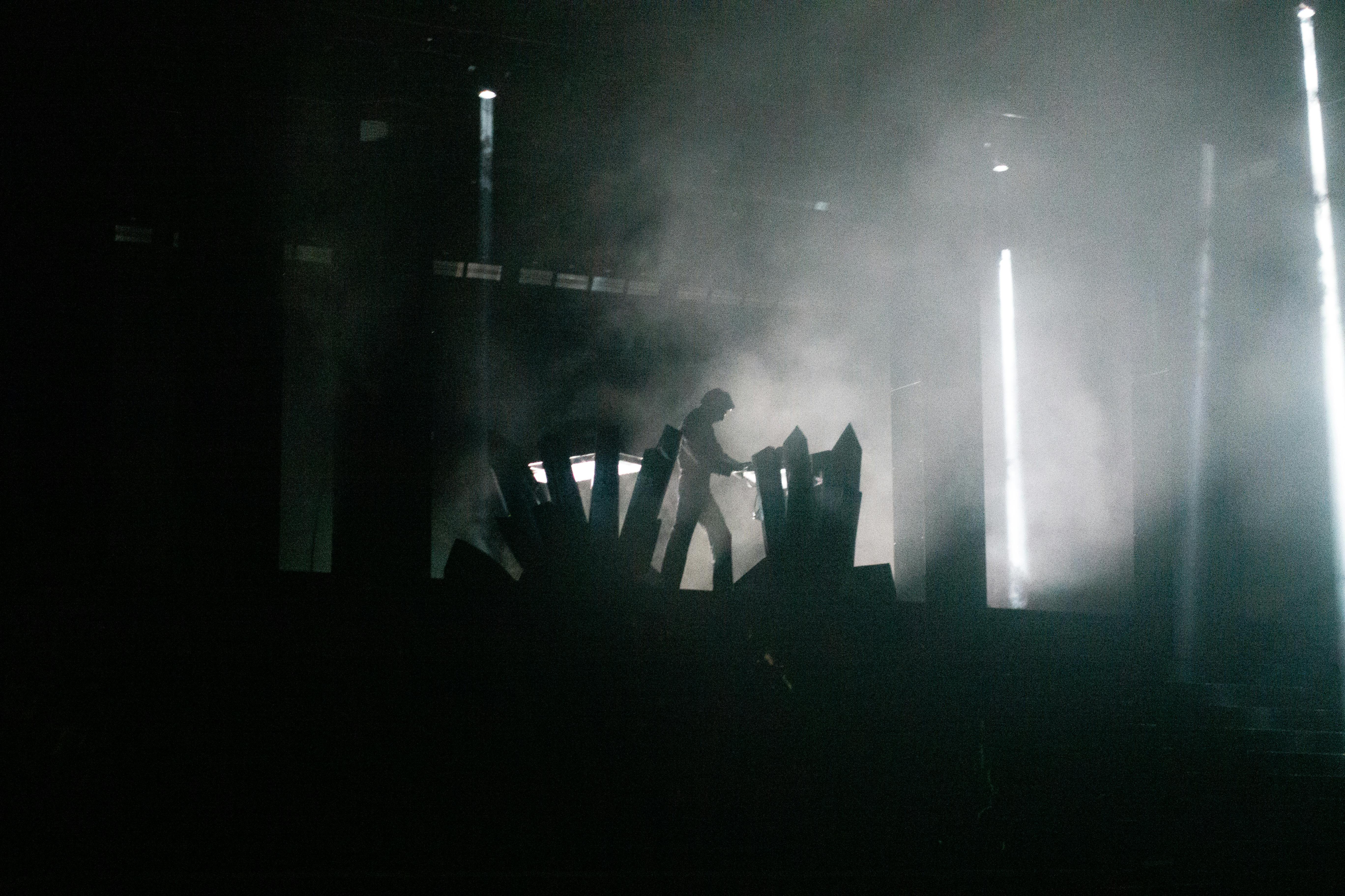 Free Silhouette of a performer on stage amidst intense lighting and smoke effects. Stock Photo