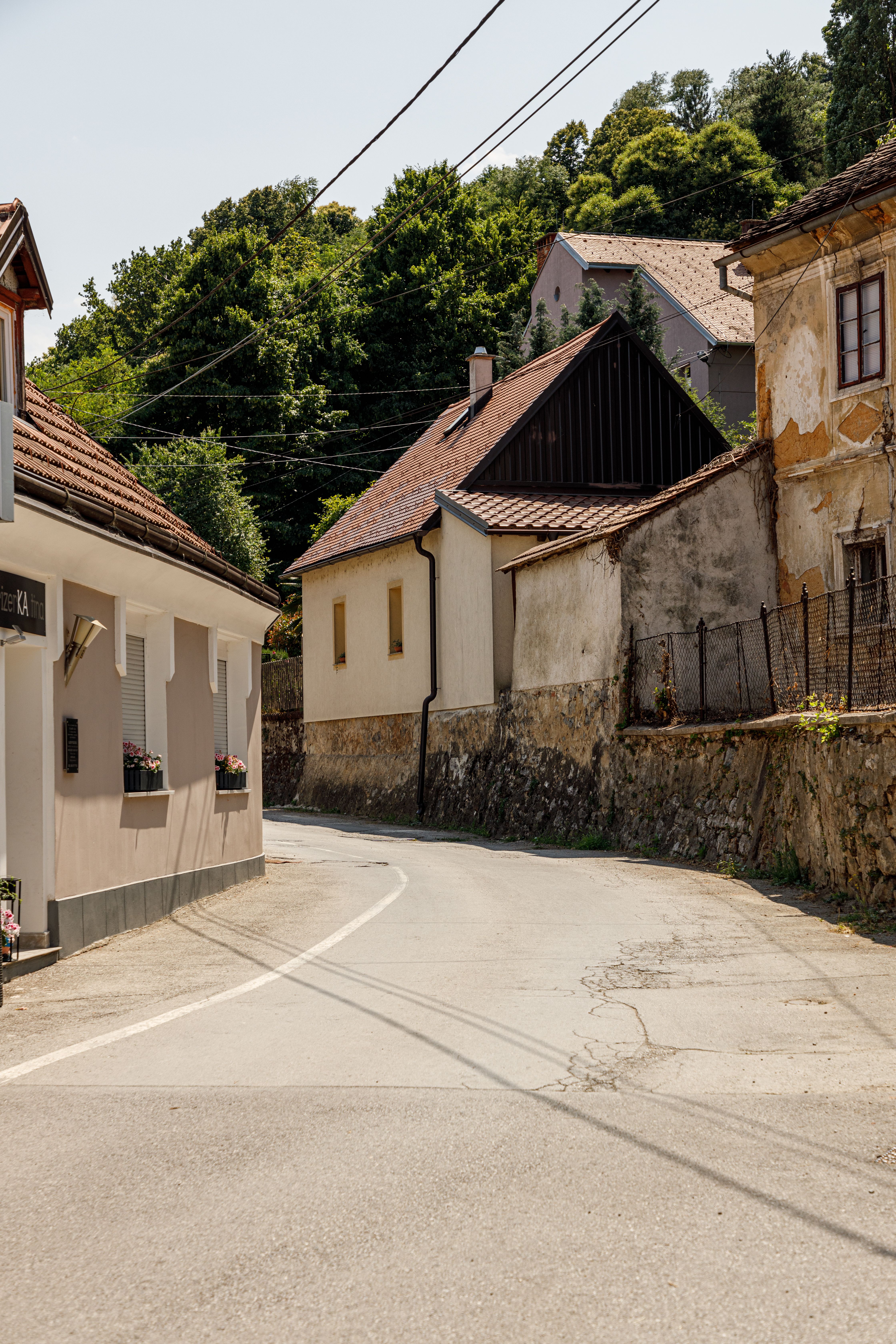 A quaint street in Karlovac, Croatia, featuring rustic architecture and lush greenery on a sunny day.