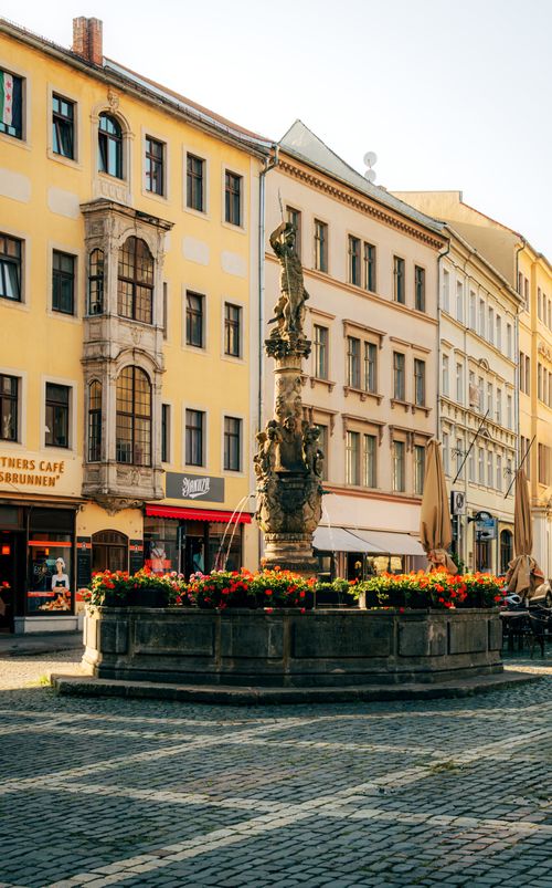 Free Charming view of a historic fountain surrounded by vibrant flowers in Zittau's picturesque old town. Stock Photo