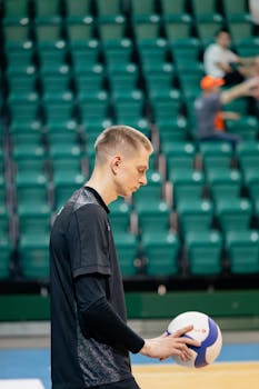 Male volleyball player focused before serving in an indoor sports arena.