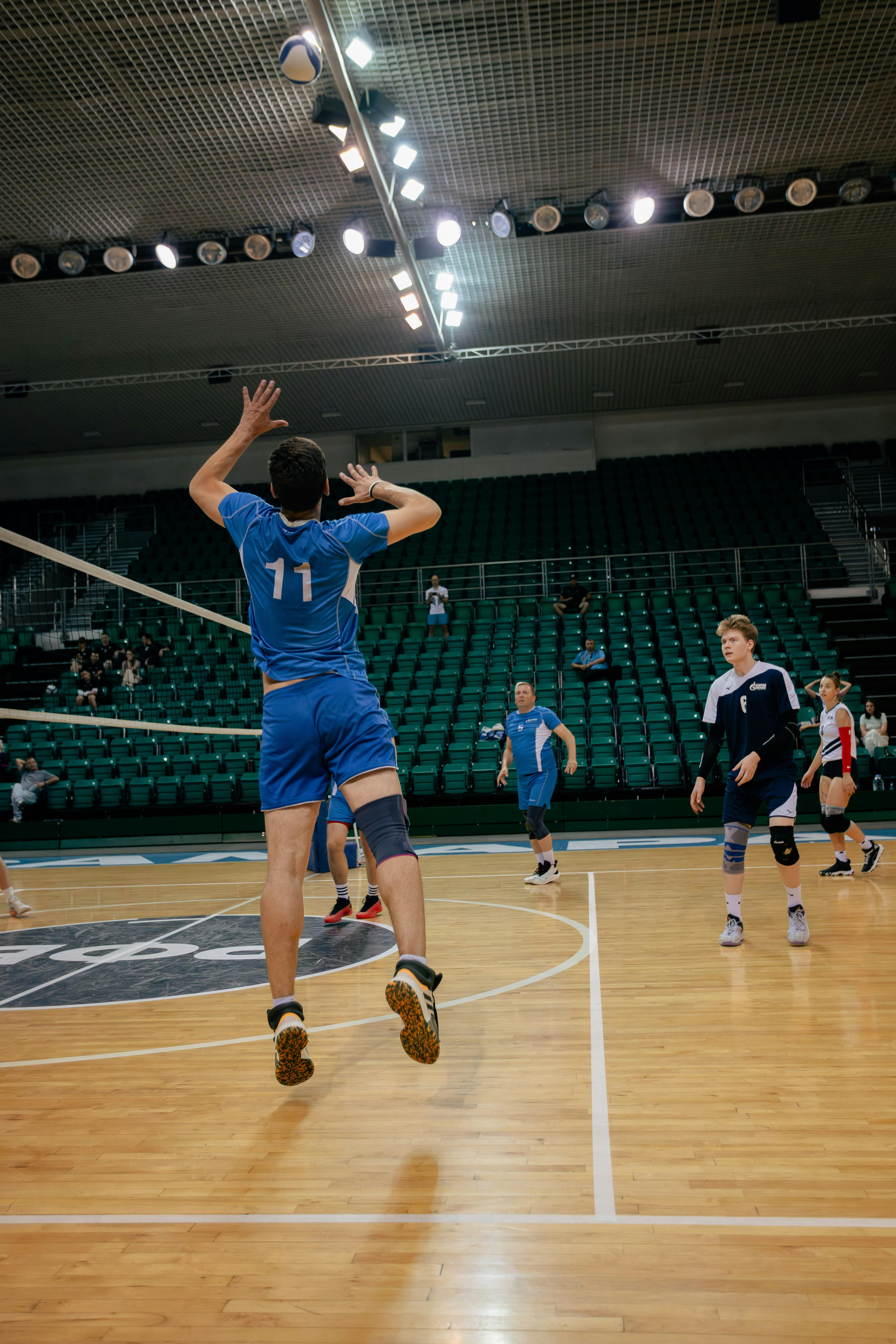 Dynamic action shot of a volleyball player serving indoors during a competitive match.