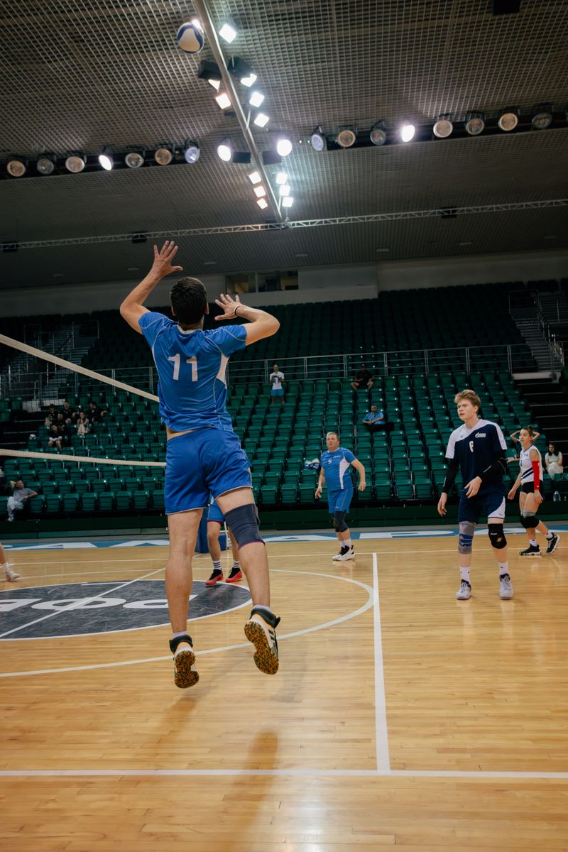 Dynamic action shot of a volleyball player serving indoors during a competitive match.